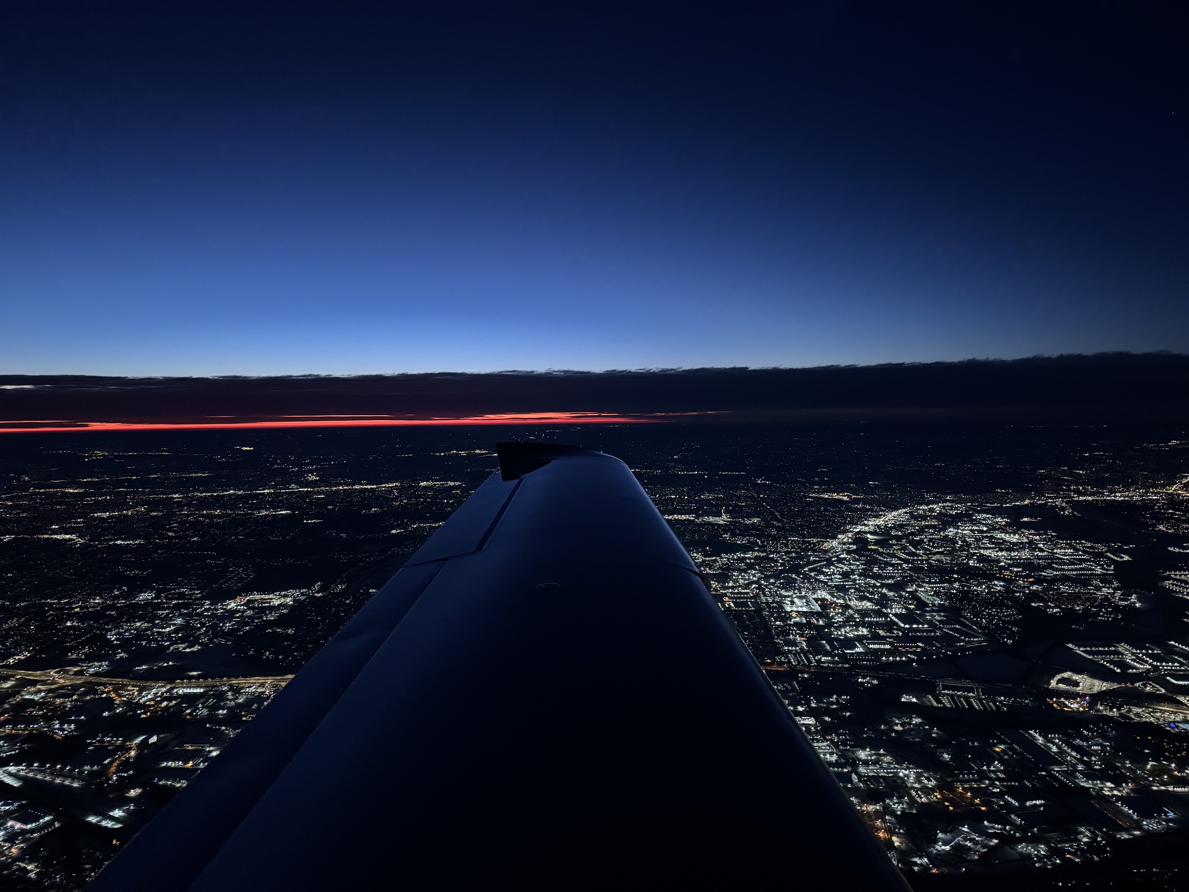 Wing over city at dusk from altitude