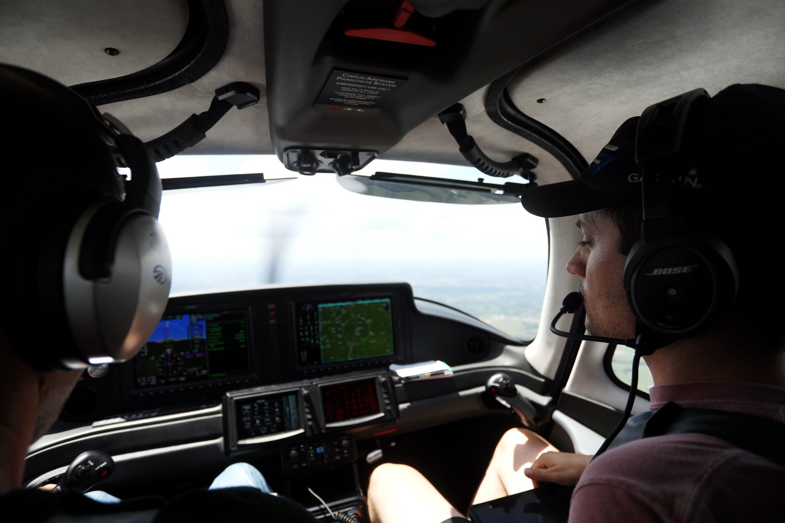 A pilot in the left seat of a Cirrus, glass panel lit, horizon out the windshield