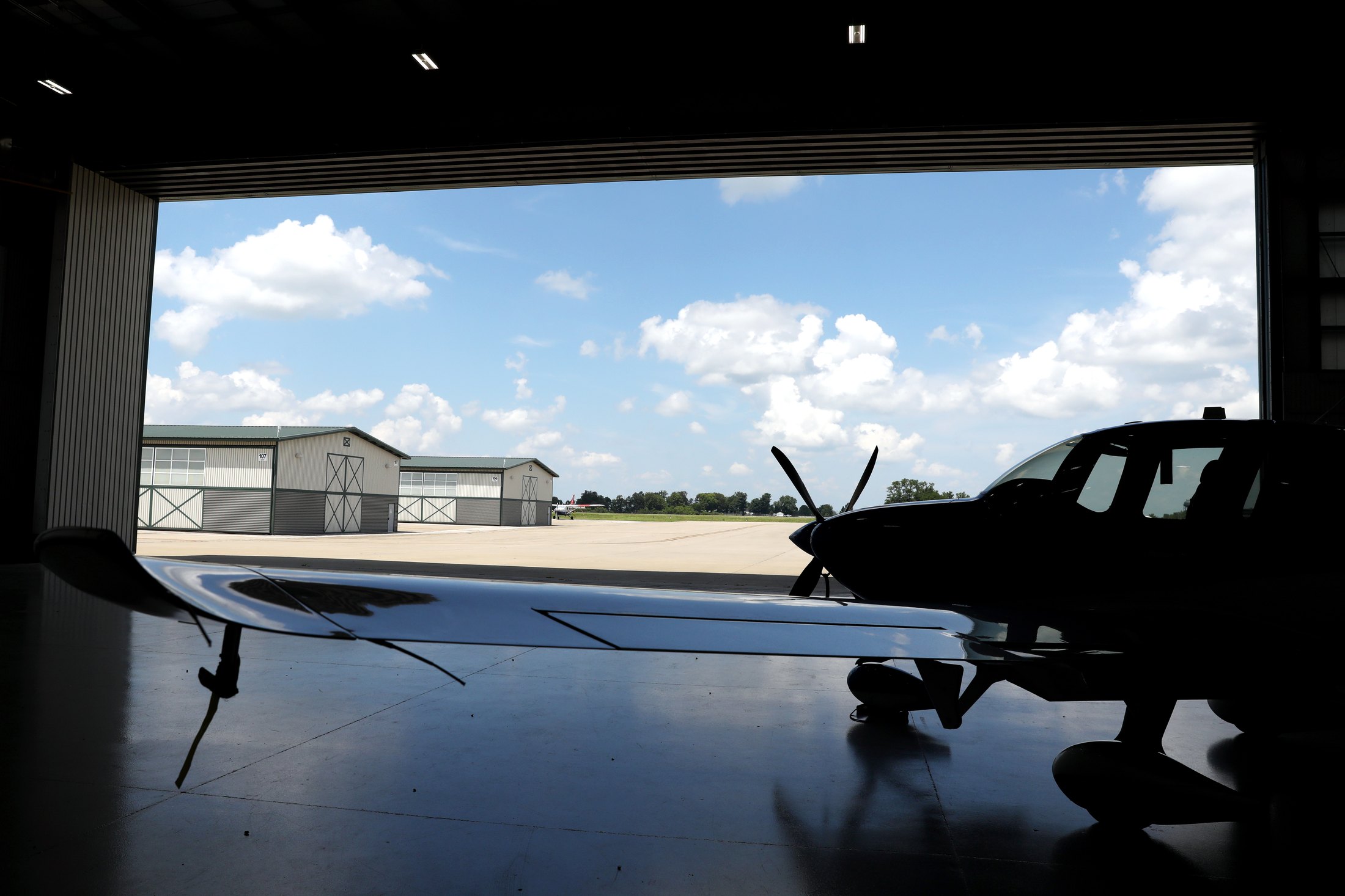 A Cirrus silhouetted in the open hangar doorway at Blue Grass Airport, the ramp and sky beyond