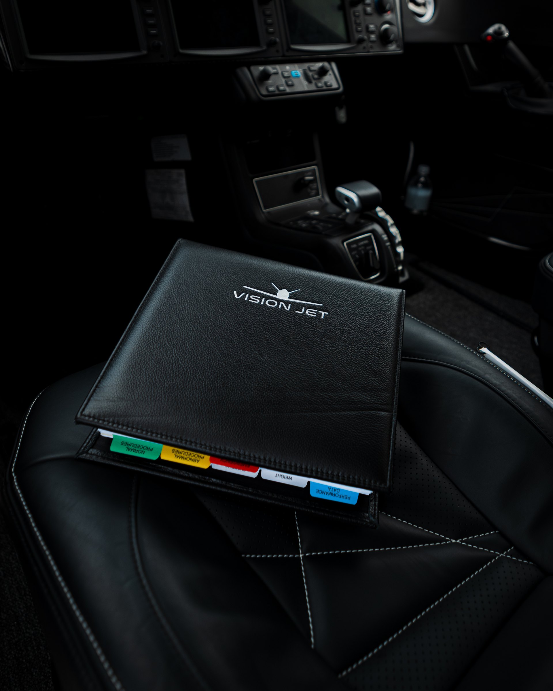 The Vision Jet pilot handbook resting on a leather seat