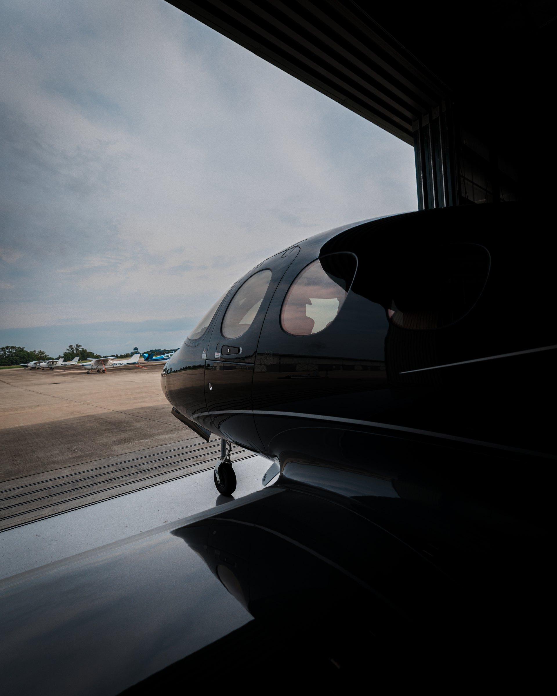 A Cirrus Vision Jet cowl and window against a wide cloudscape