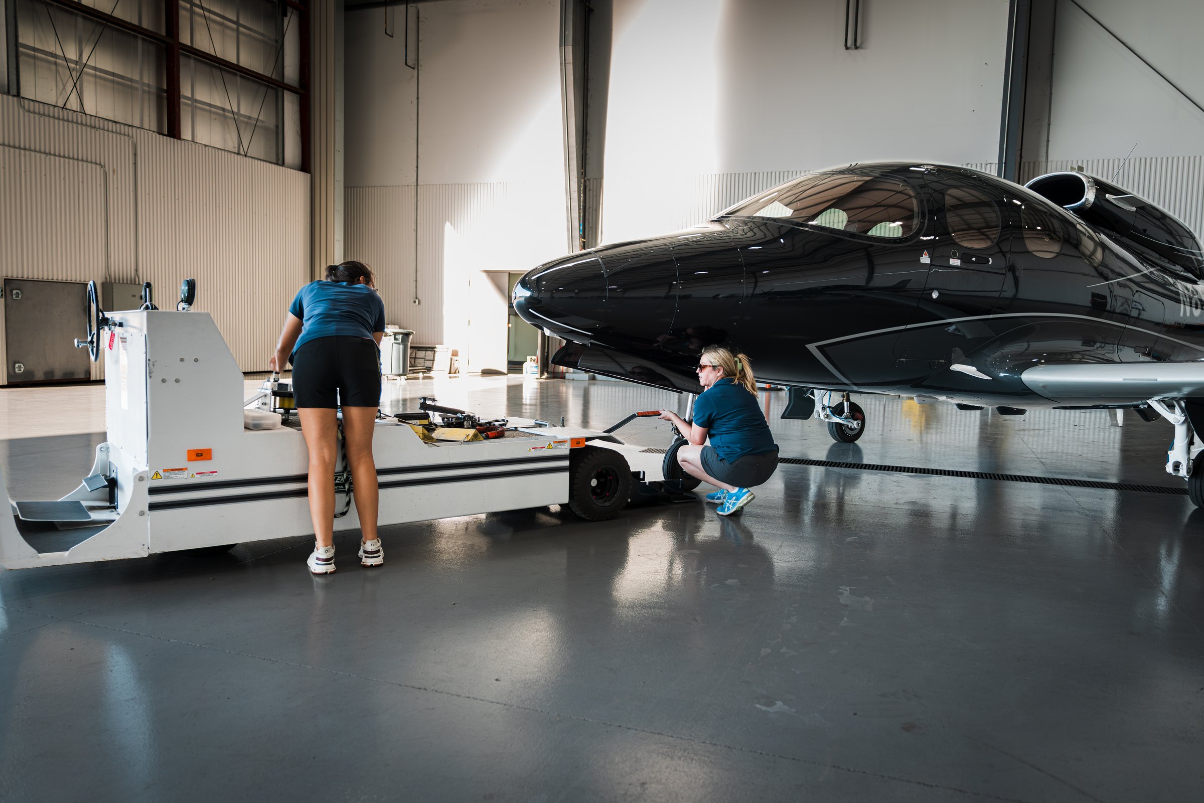 Two AeroVision team members caring for the Vision Jet inside the hangar