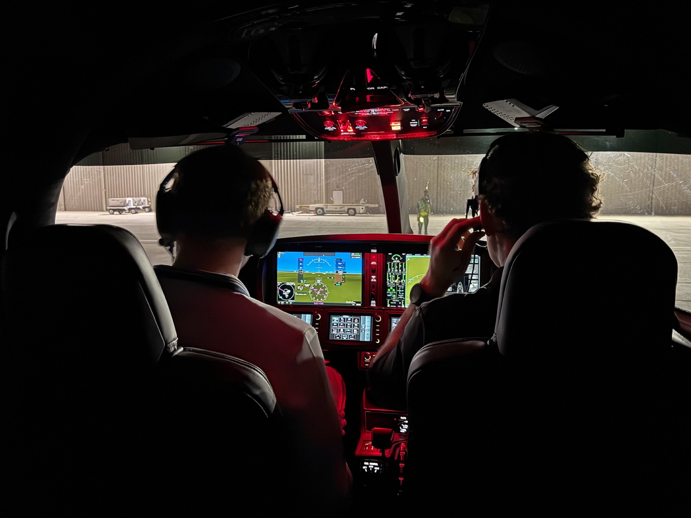 Two pilots in a Vision Jet cockpit at night