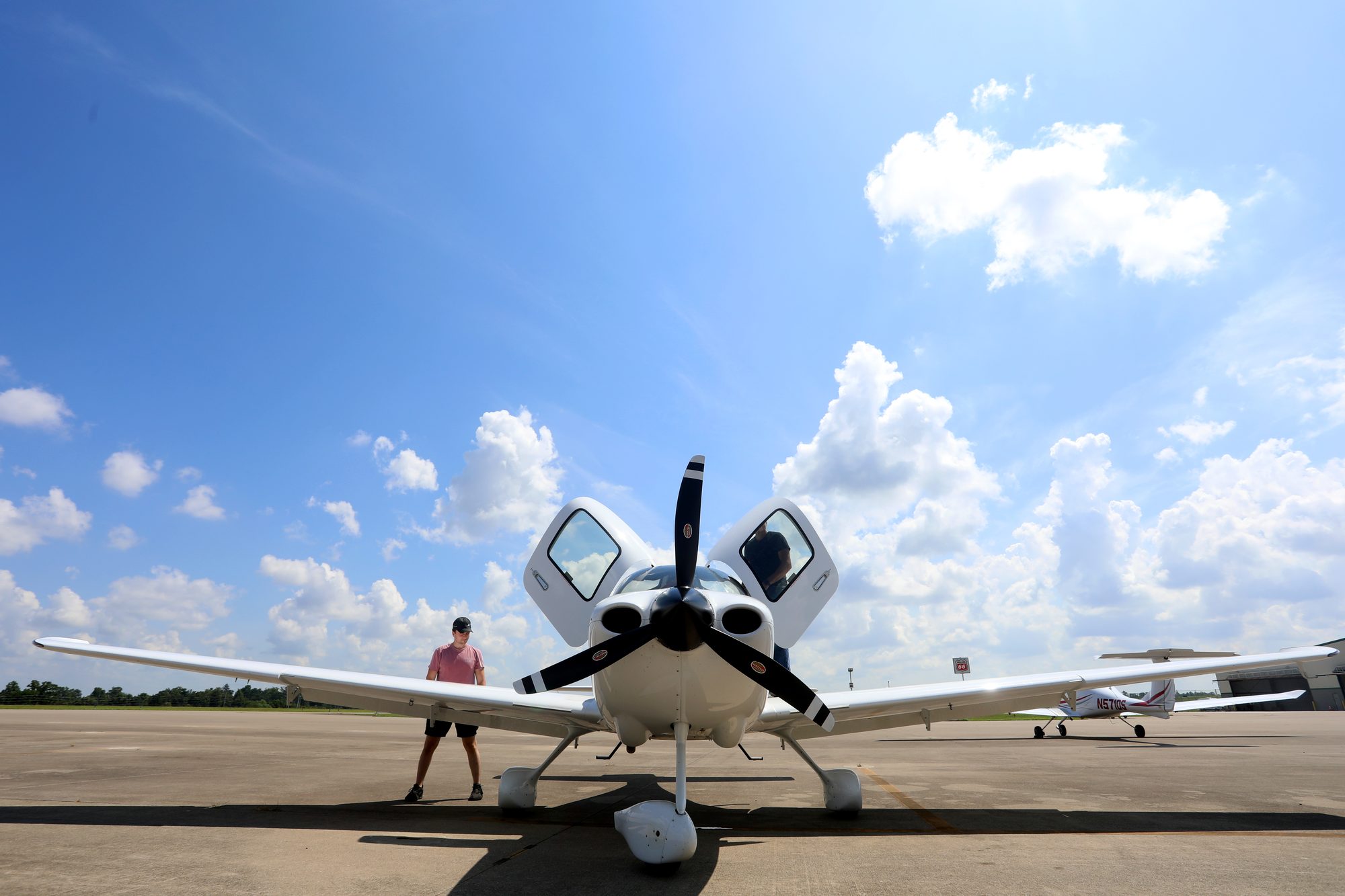 A Cirrus SR20 on the ramp at Blue Grass Airport, doors open under a summer sky
