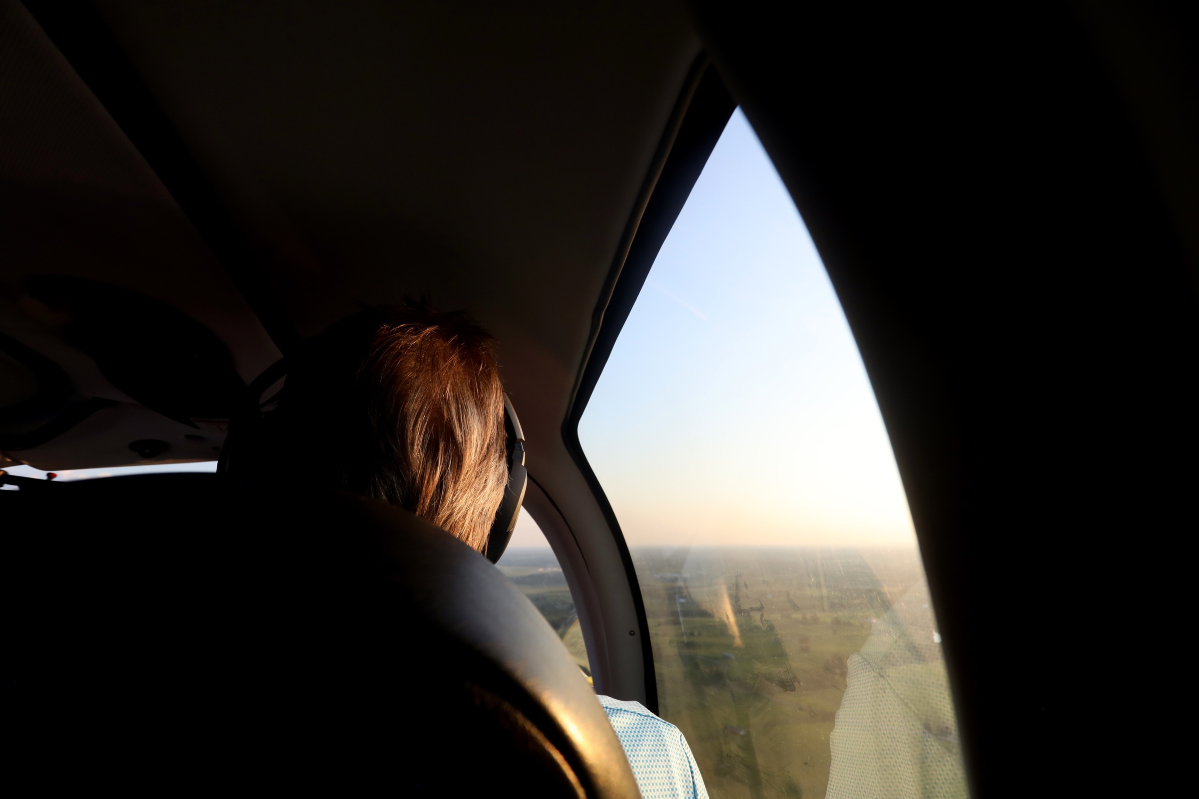 Passenger looking out the cabin window at sunset